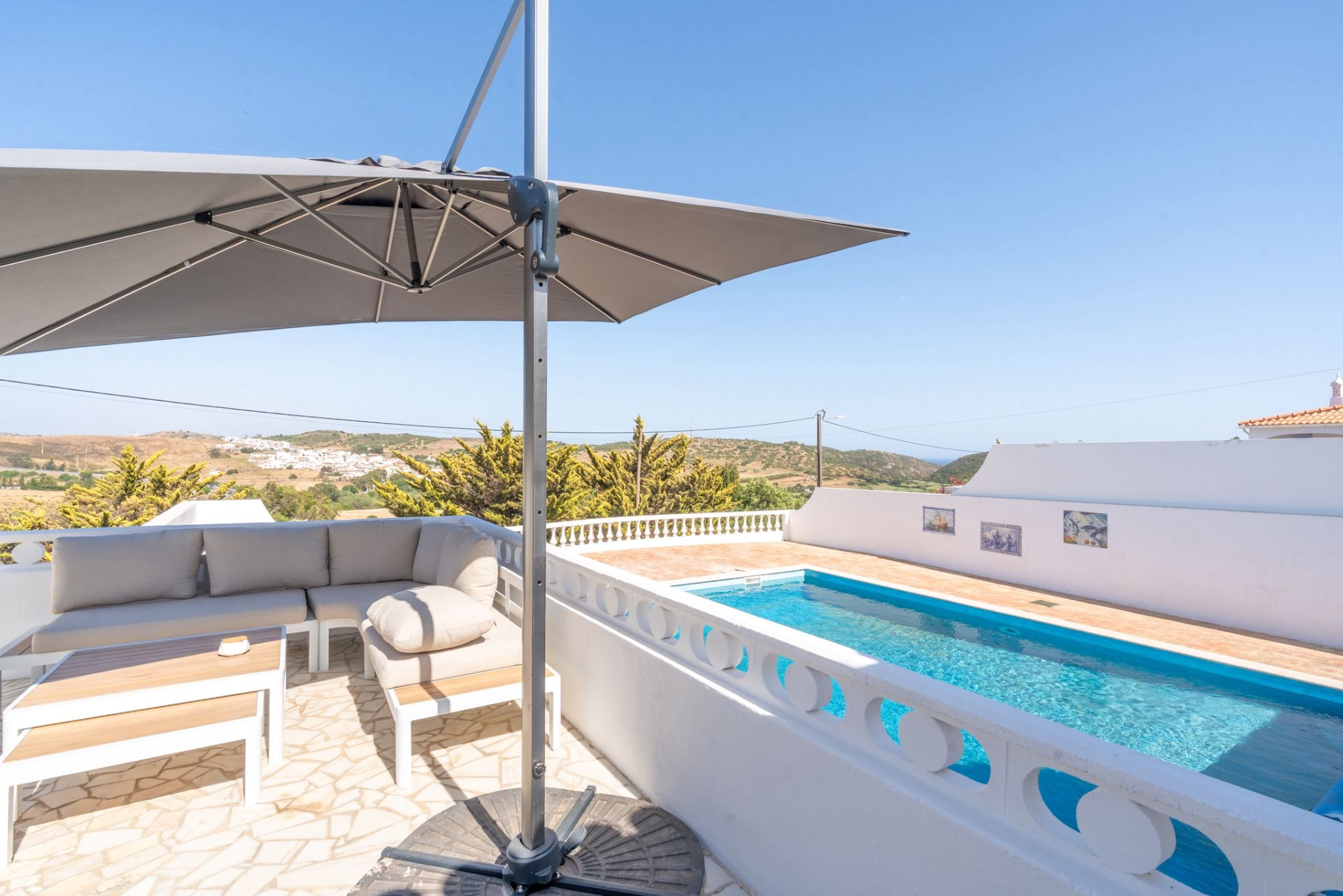 Shaded terrace lounge beside the pool with views over the hills