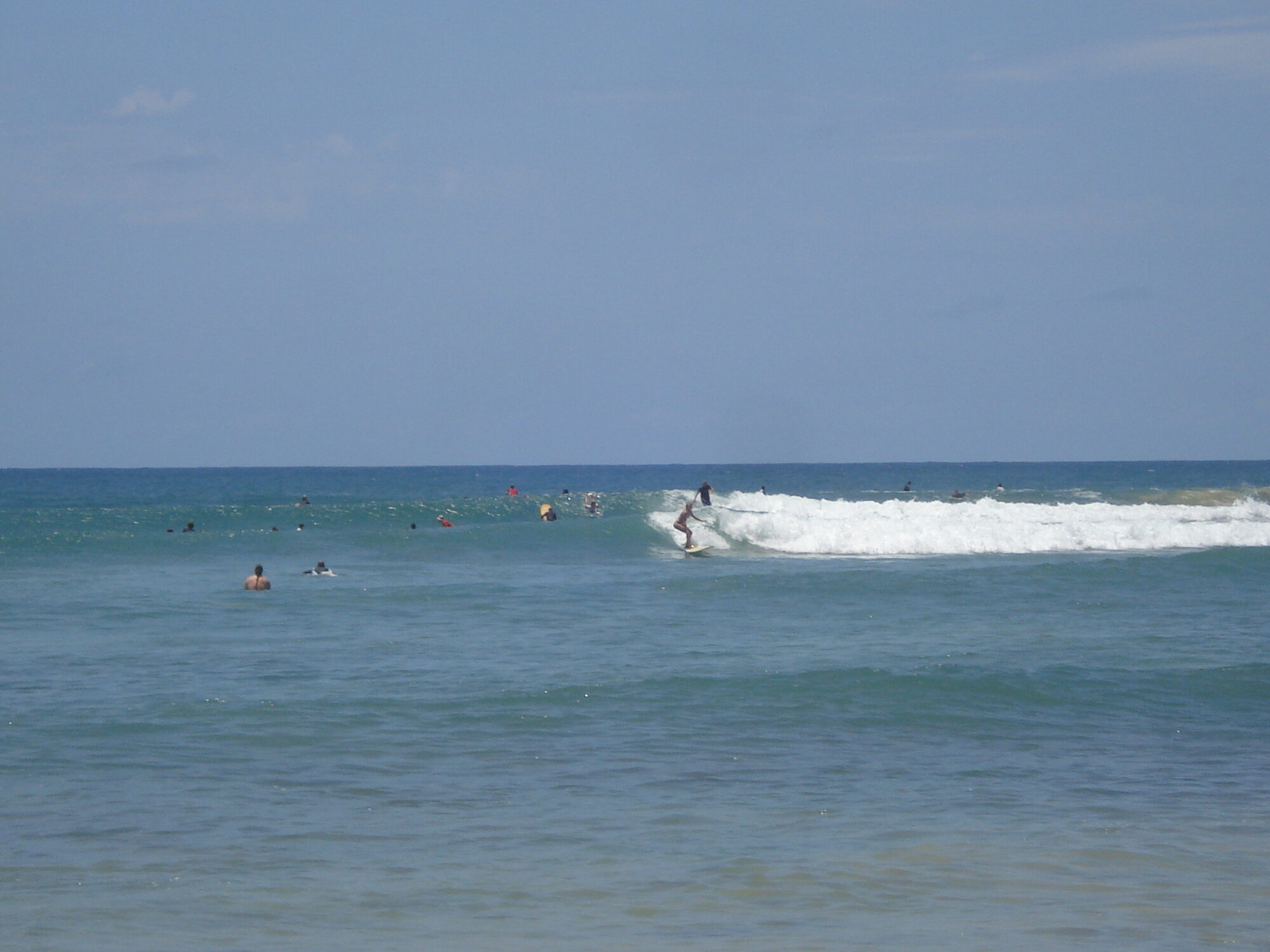 Surfers waiting in a clean line-up on calm turquoise water